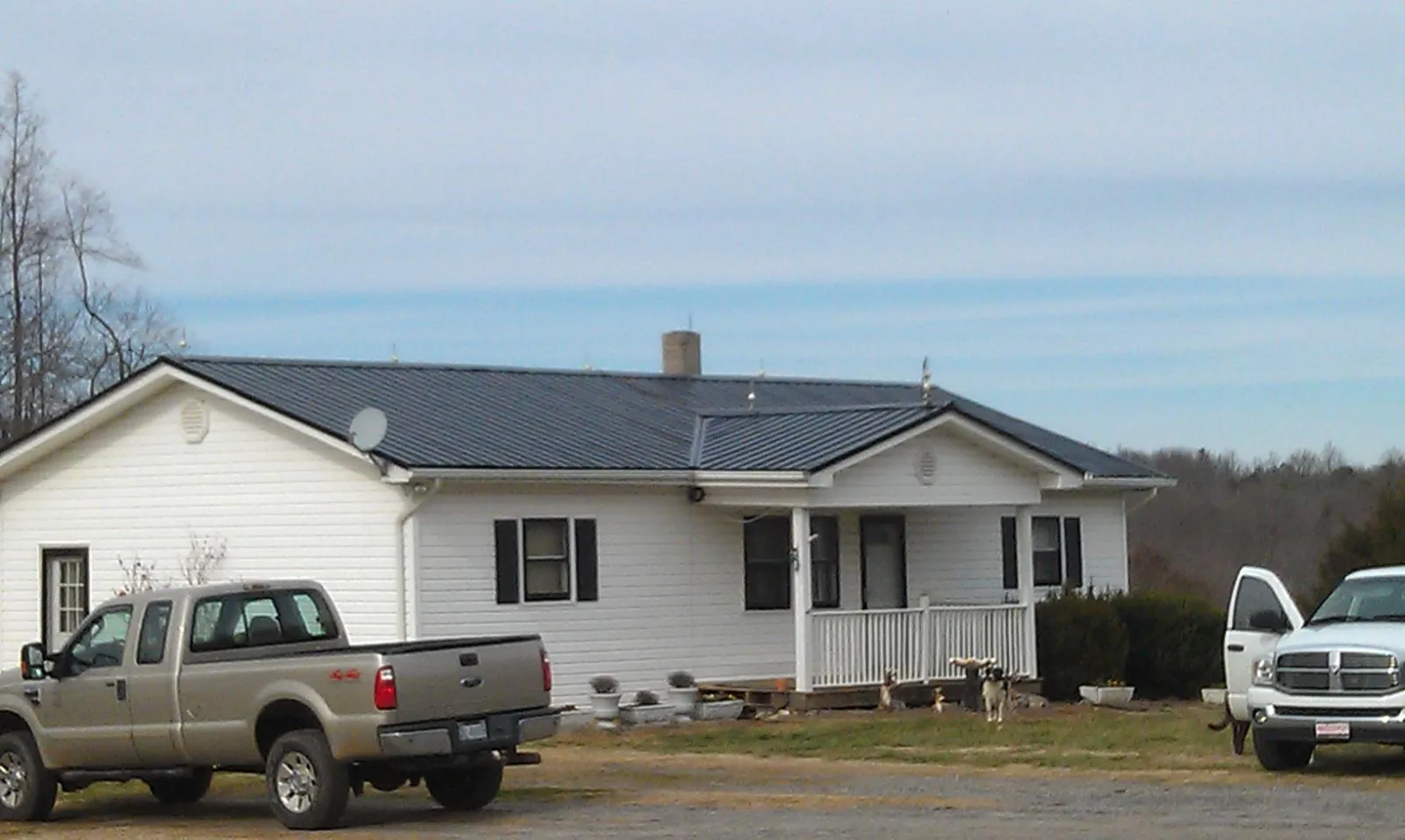 Finished dark metal roof on a white ranch home with work trucks parked in Danville